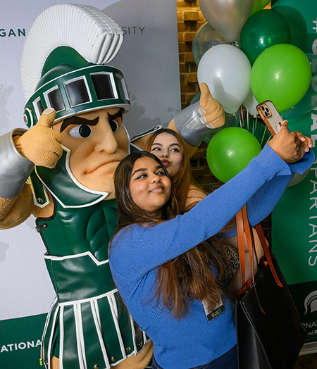 Sparty poses for a selfie with students.