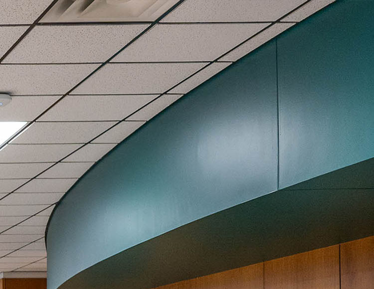 White ceiling tiles, a turquoise rounded shape and wood paneling.