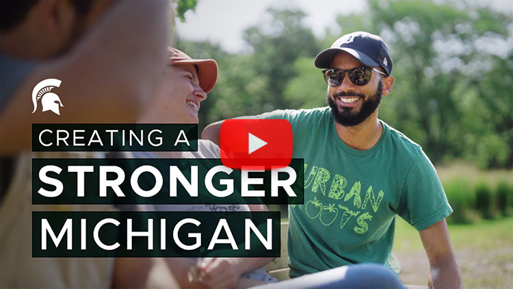 Individuals chatting outside with text that says: Creating a stronger Michigan with a Spartan helmet.